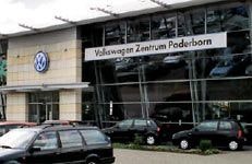 Außenansicht des Volkswagen Zentrums Paderborn aus dem Jahr 1995. Das moderne Gebäude mit großer Glasfassade trägt das Volkswagen-Logo und den Schriftzug des Autohauses. Mehrere schwarze Fahrzeuge stehen vor dem Eingangsbereich geparkt.