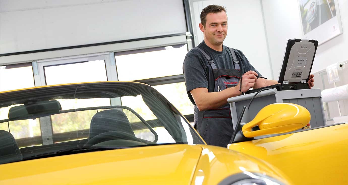 Werkstattmitarbeiter im Porsche Zentrum Paderborn führt eine Fahrzeugdiagnose mit dem Laptop durch – Präzision und modernste Technik im Service.