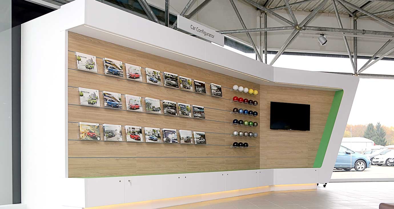 Car Configurator im Autohaus Thiel in Schloß Neuhaus – Präsentationswand mit Škoda-Fahrzeugbroschüren, Lackfarbmuster und integriertem Bildschirm für individuelle Fahrzeugkonfiguration.