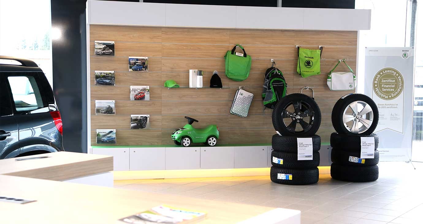 Zubehör- und Merchandising-Bereich im Autohaus Thiel in Schloß Neuhaus – Präsentation von Škoda-Fanartikeln, Werbematerialien und Winterreifen auf Felgen.